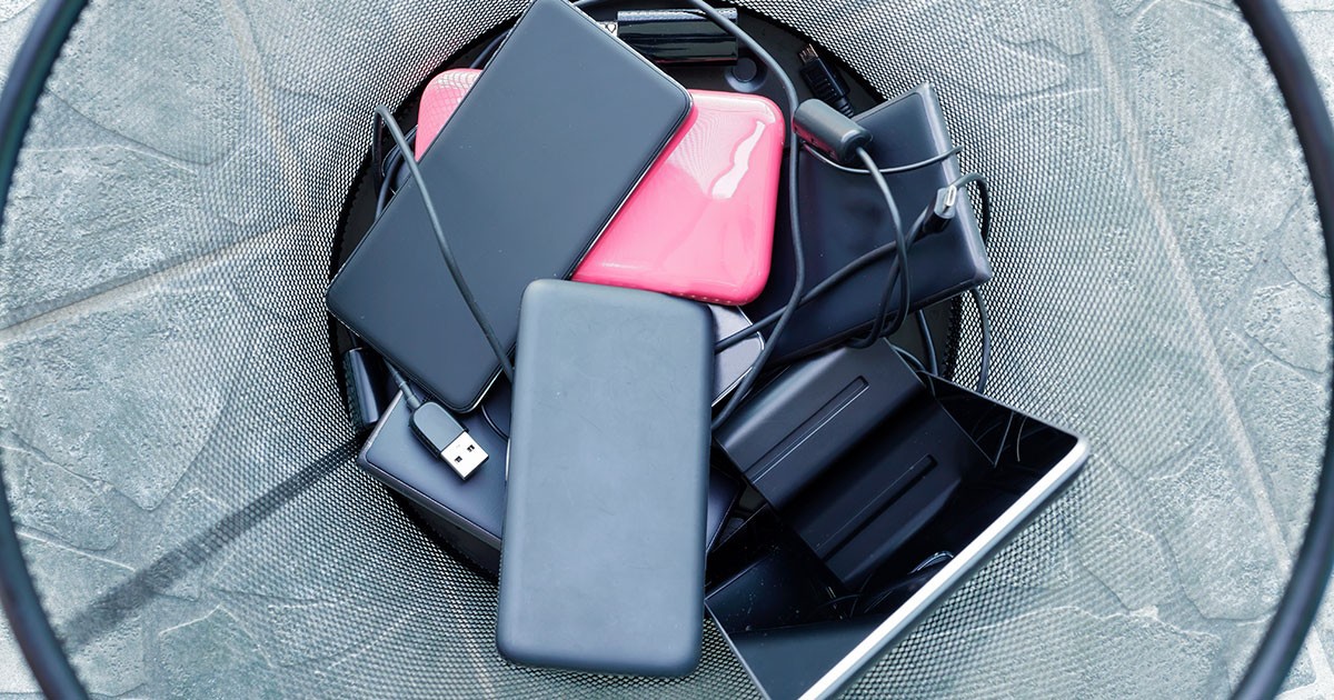 several smartphones and tablets in trash can