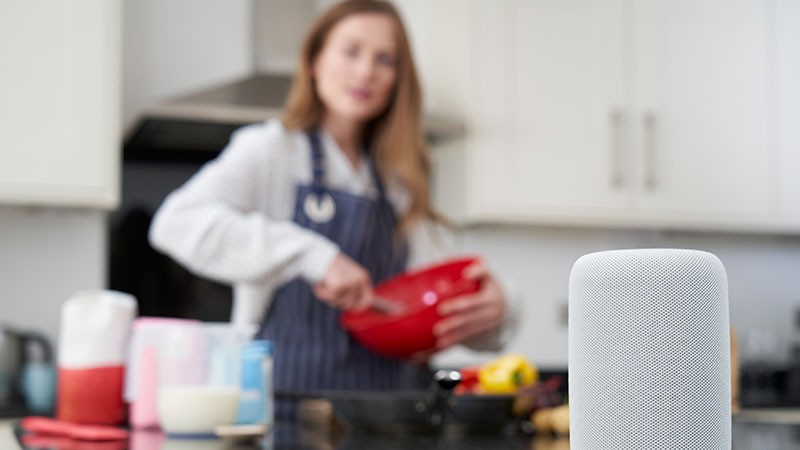 woman bakes a cake and adds to her grocery list using a smart speaker