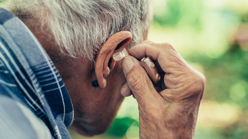 Senior man inserts a hearing aid