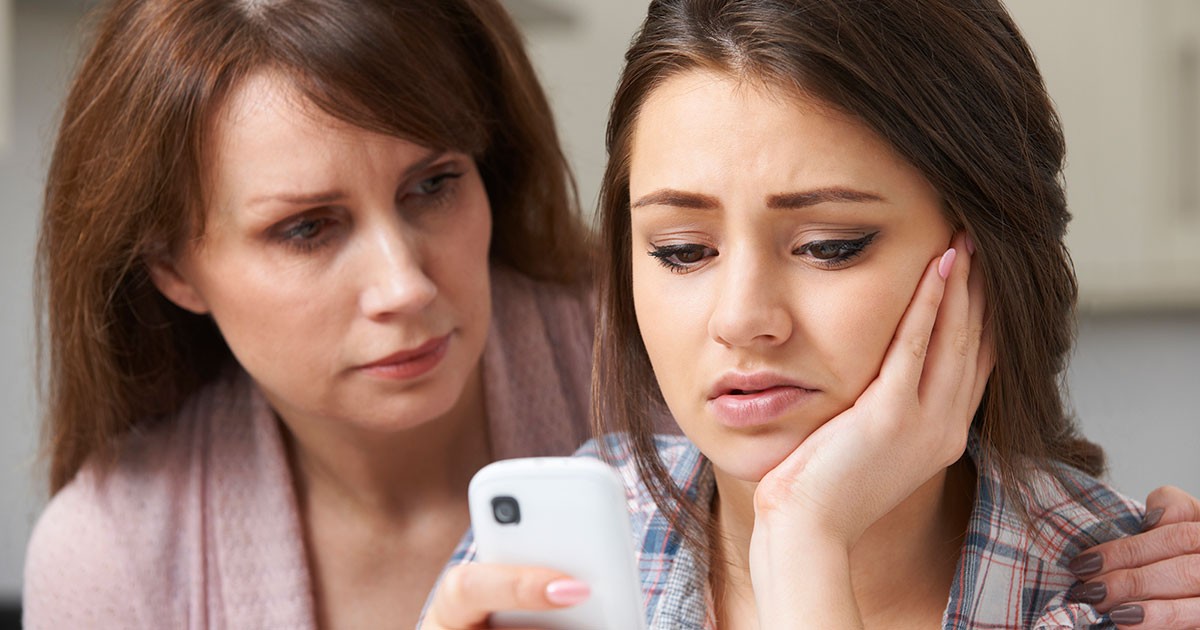 A mother comforts her daughter over the cyberbullying she is experiencing.