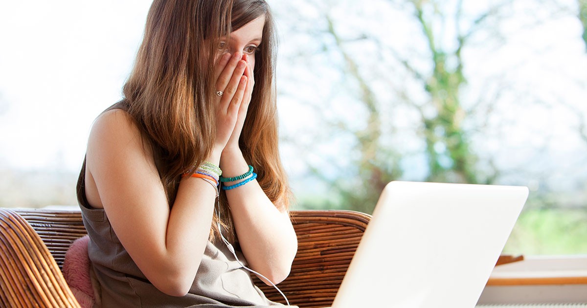 Teen girl in shock looking at laptop