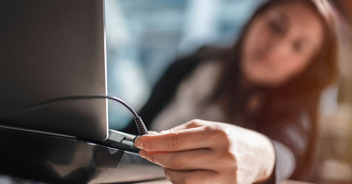 Woman checks the charging cable for her laptop.