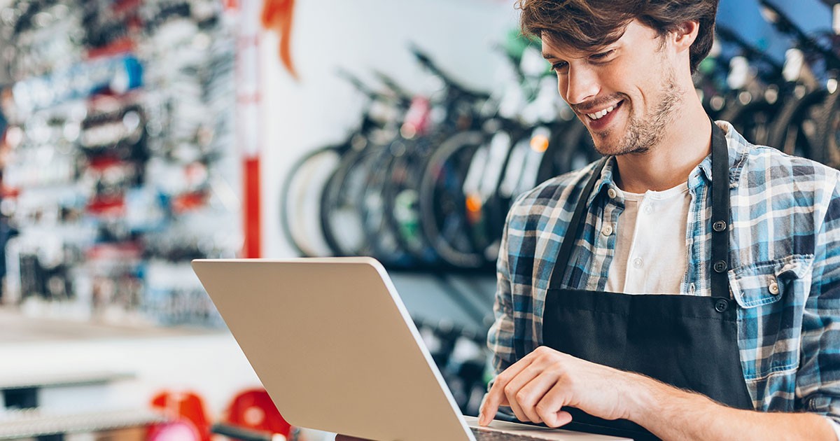 Male bike shop owner uses his laptop to run his small business