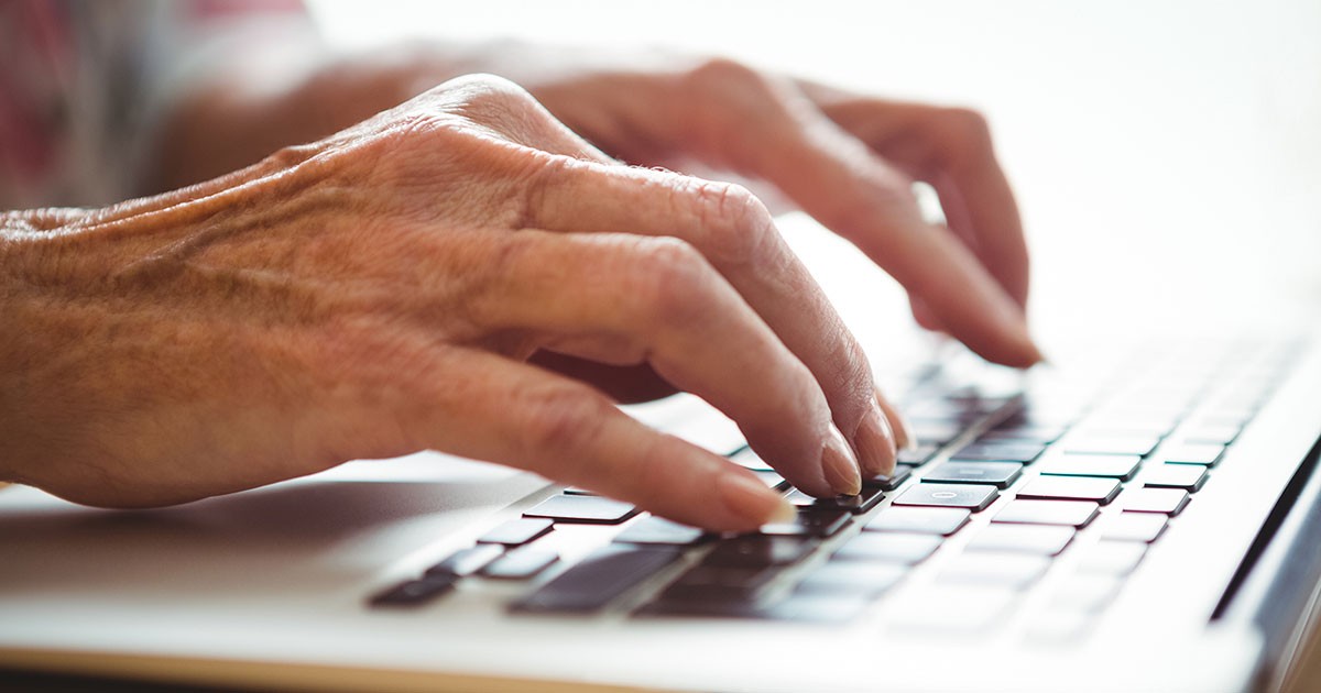 A senior citizen uses a keyboard to write a message on social media