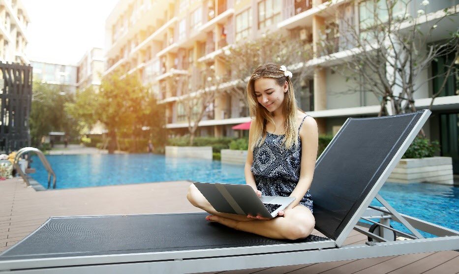 A resident accesses WiFi on her laptop next to her community pool