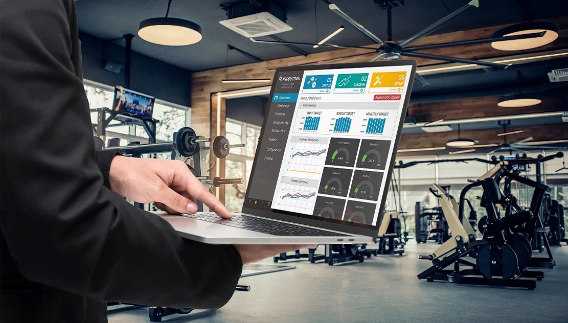 Person manages fitness center through a laptop using multifamily technology solutions