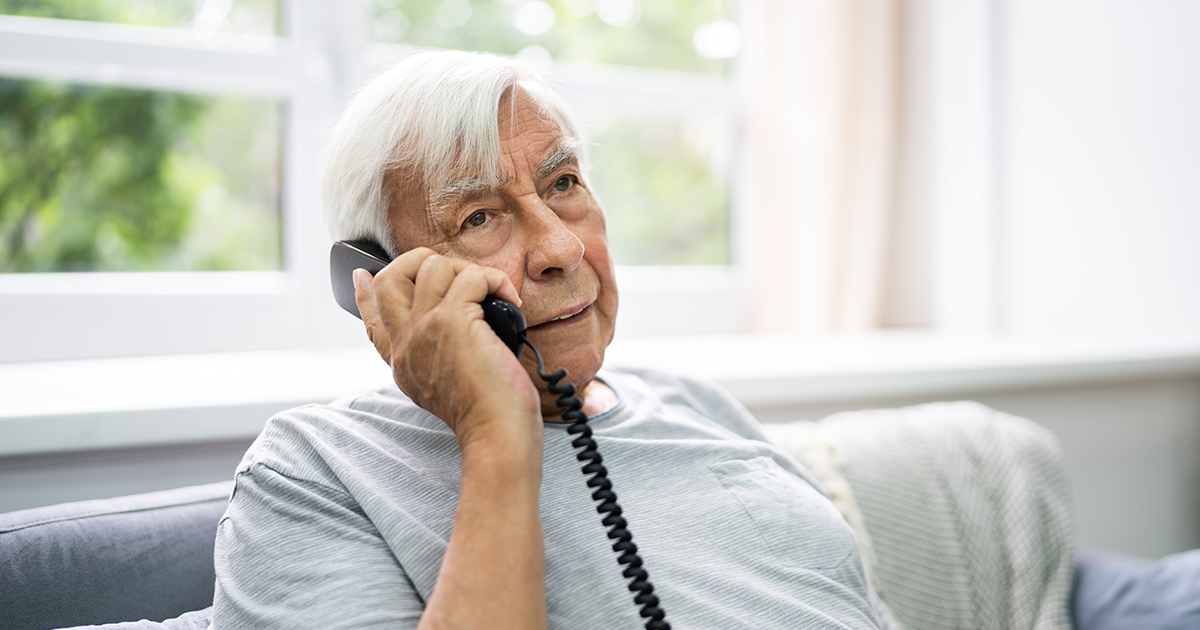 Elderly man uses a landline phone