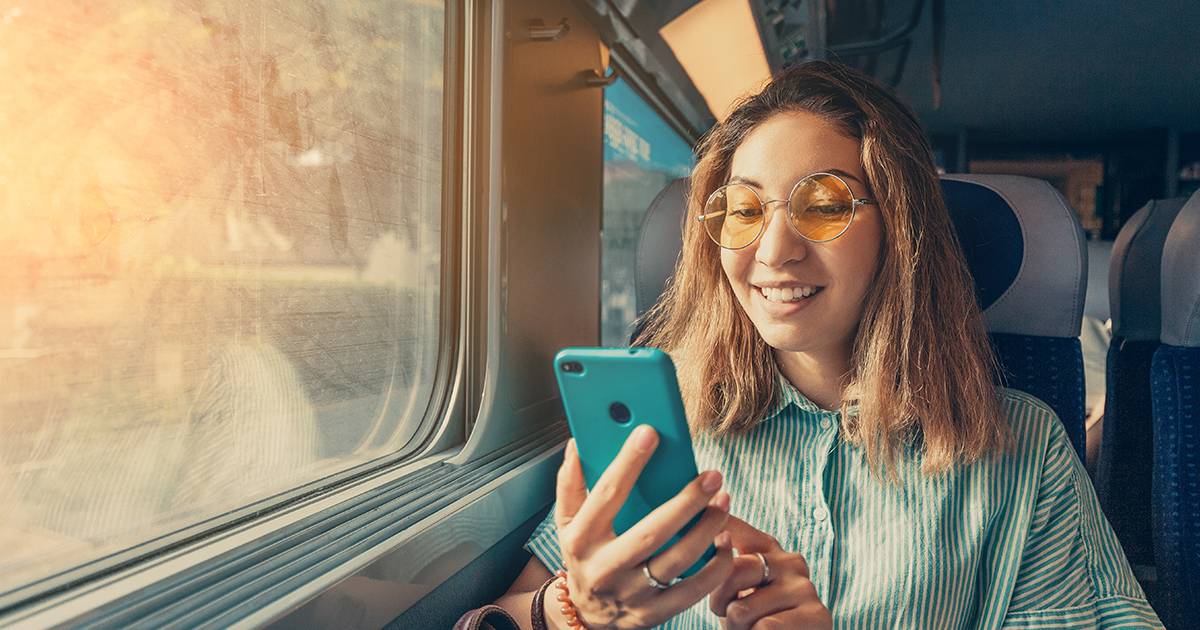A woman on a train manages her vacation plans with an app
