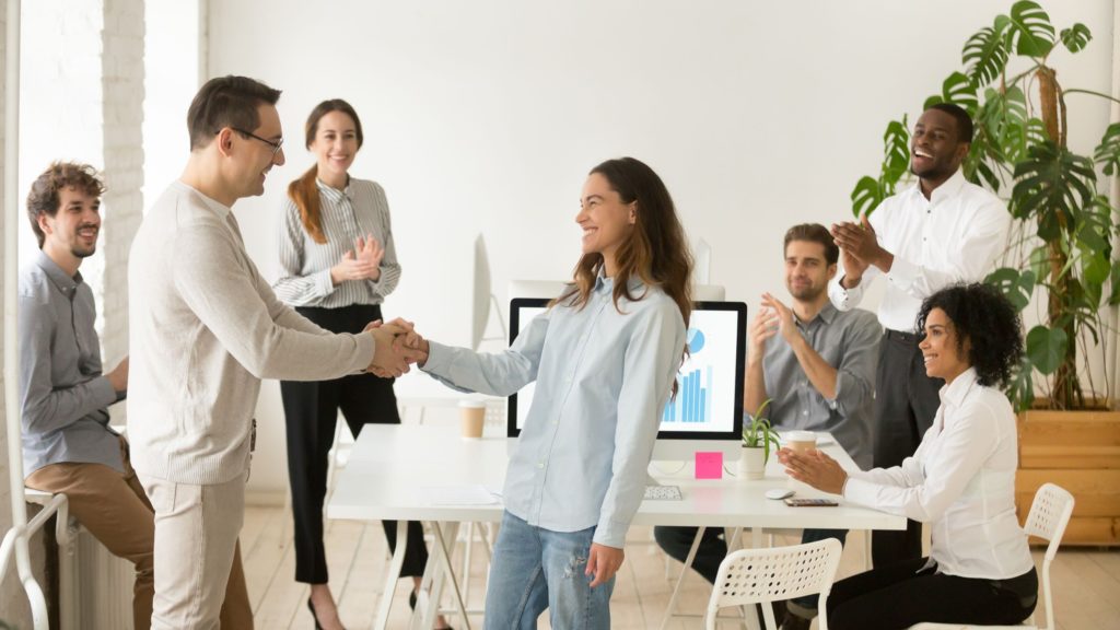 Employee is recognized in front of her peers at work by her boss. 