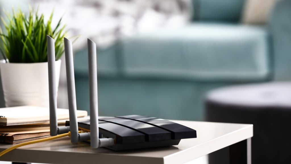 A router rests on a side table in a living room. 