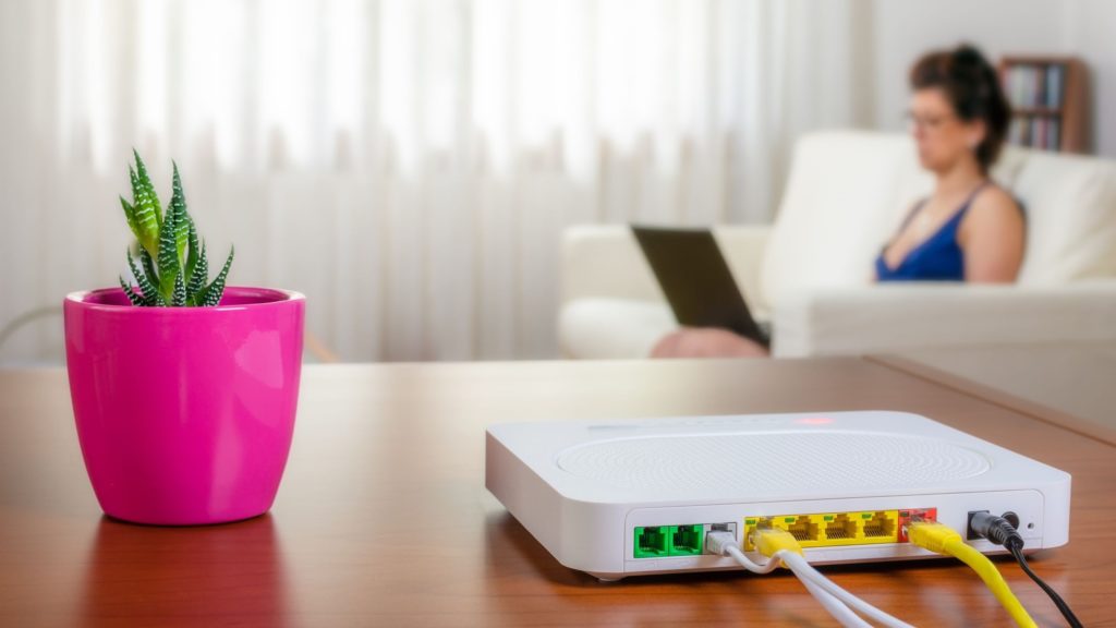 A modem sits on a table next to a plant. 