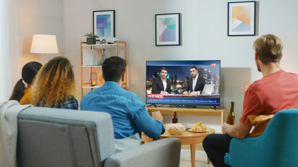 A group of friends watches live news on streaming TV. 