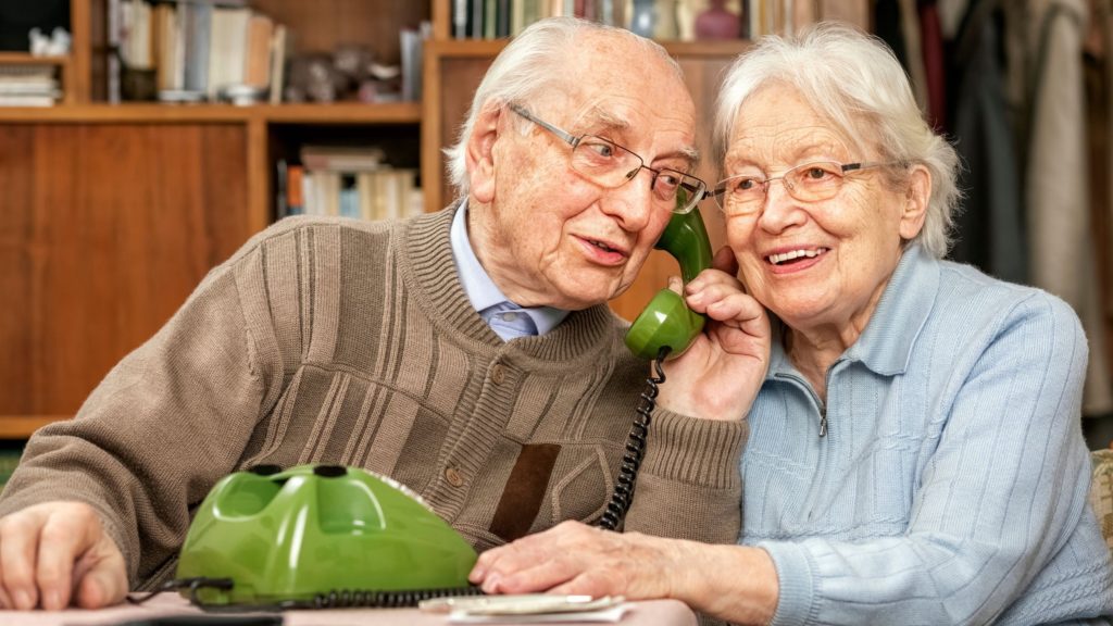 Elderly couple uses a green landline phone.