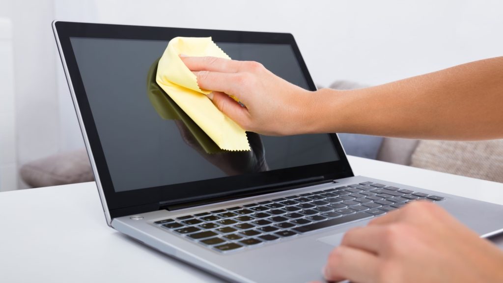 Person cleans a laptop screen with a microfiber cloth. 