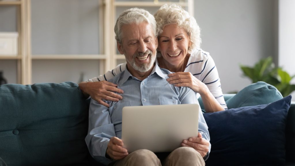 An older couple video chats with family members on a laptop using ethernet or wifi.