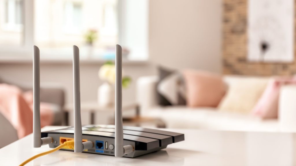 A router sits on a tabletop in a living room. 