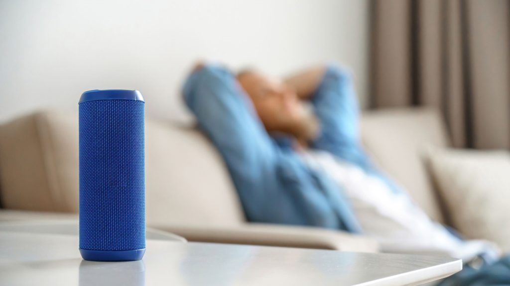 A person enjoys listening to music on a wireless speaker. 
