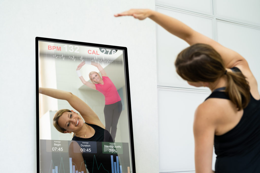 Woman using an interactive mirror in her smart home gym