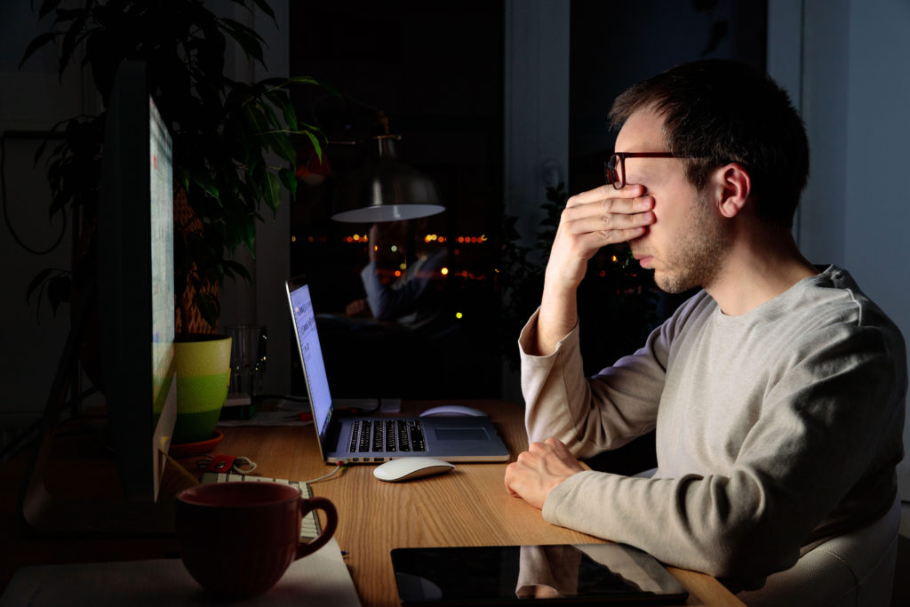 Man in dark room dealing with digital eye strain